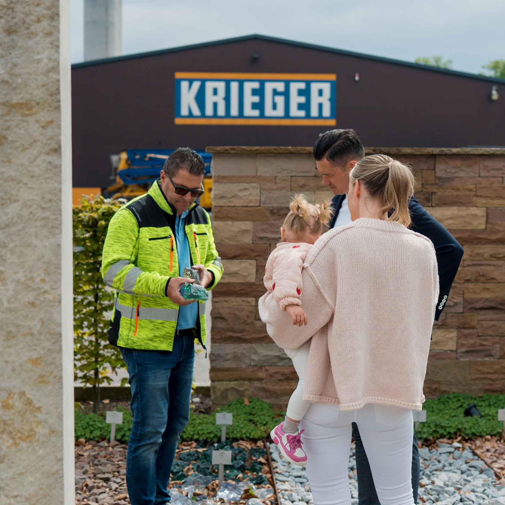 Ein Berater der Krieger Gruppe berät eine Familie bei der Auswahl von Natursteinen für ihren Garten.